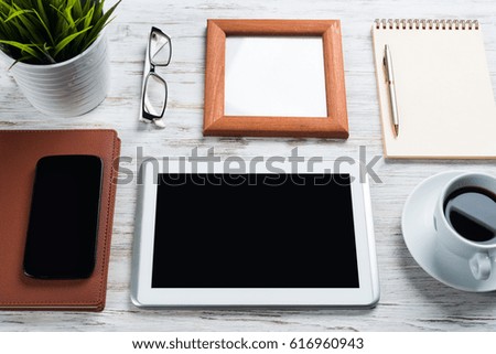 Still life photo of tablet notepad coffee glasses on wooden table