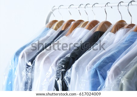 Rack of clean clothes hanging on hangers at dry-cleaning Royalty-Free Stock Photo #617024009