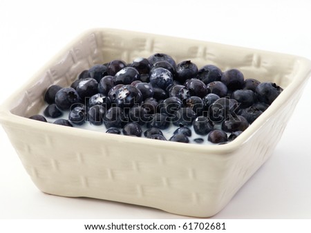 Blueberries in a square bowl with milk on a white background and copy space