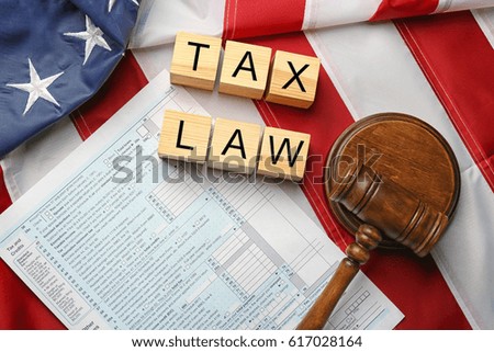 Wooden cubes with space for text, judge gavel and tax forms on American flag background