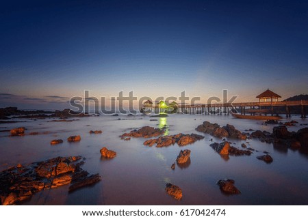 The view of burning sunrise at beach with jetty at Tanjung Balau Kota Tinggi Johor Malaysia. This image may contain noise and blurry clouds due to long exposure, soft focus and poor lighting