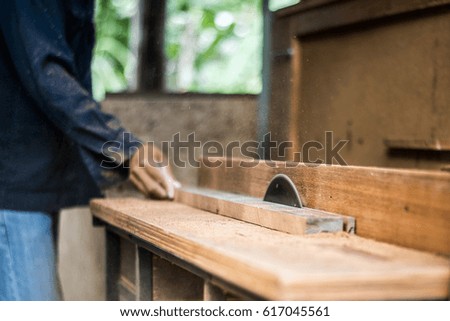 Closeup of carpenter cutting a wooden plank with a circular saw