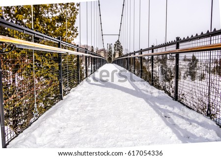 Snow covered suspended bridge over a waterfall