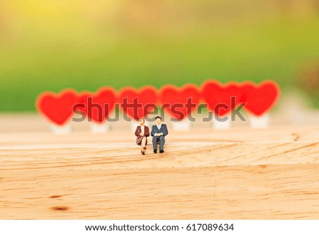 Miniature couple sitting on red heart , valentine concept.