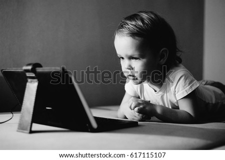 Little boy watching video on the tablet. Monochrome portrait.
