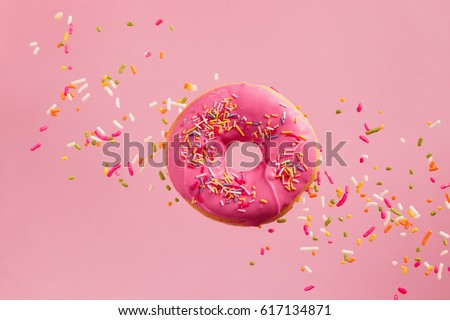 Sprinkled Pink Donut. Frosted sprinkled donut on pink background. Royalty-Free Stock Photo #617134871