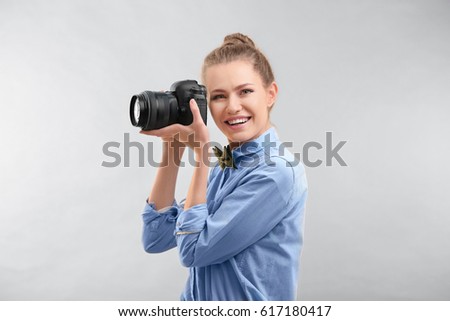 Beautiful female tourist with camera on light background