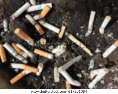 Blur picture of cigarettes stub with ash on the sand tray.