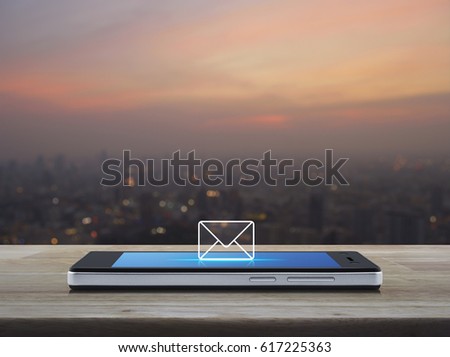 email icon on modern smart phone screen on wooden table over blur of cityscape on warm light sundown, Business communication concept