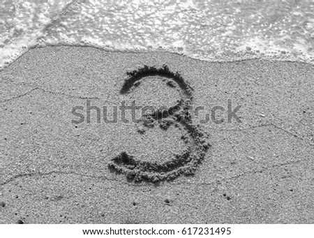 black and white picture handwriting font number three on nature sand at the seaside beach 