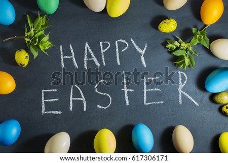Easter composition with colorful eggs on a dark blue background. With the inscription of the Happy Easter chalk