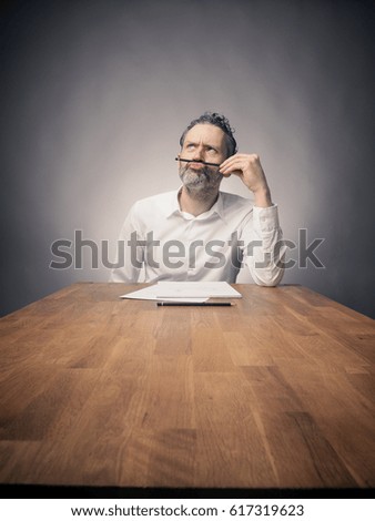 Crazy business man working on a wooden office table, wide angle shot with space for text or image