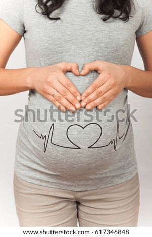 A pregnant girl in a gray T-shirt, with a funny picture.