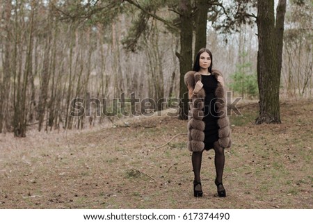Portrait of a very beautiful girl in a forest dressed in fur