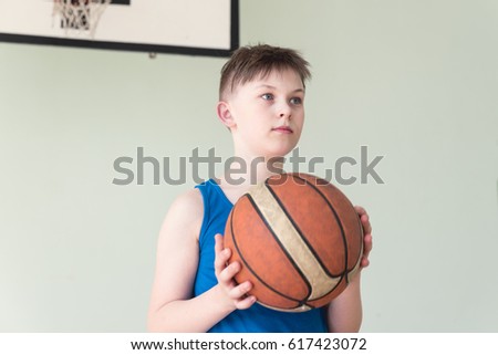 A caucasian boy in blue shirt holding basket ball