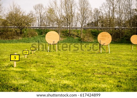 Target at an archery range in a meadow with distance signs next to it