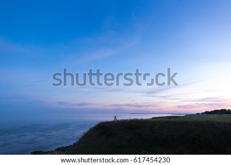 Beautiful athletic girl doing yoga against the sea. Sporty woman get gymnastic exercises near the ocean. Silhouette Girl in sportswear doing outdoor work-out, sunset. Empty space for the text.