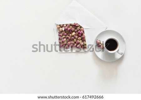 Purple dry roses in envelope and cup of tea on white background, flat lay, overhead view,