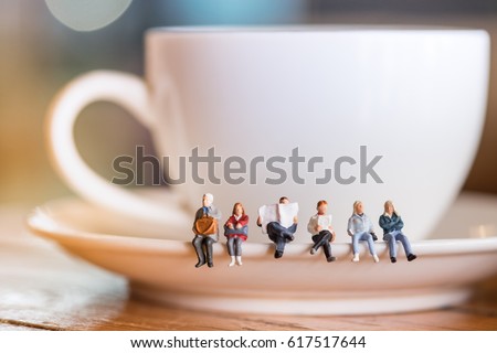 Group of miniature people figures sitting, waiting and reading newspaper and book on white plate of cup of hot coffee at coffee shop. Royalty-Free Stock Photo #617517644