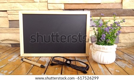 chalk board , pen and flower on wooden background