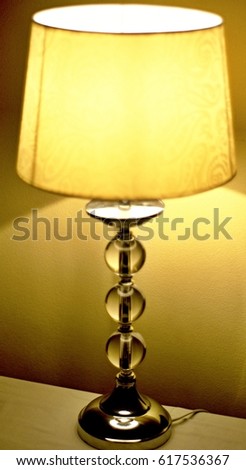 Golden Table Lamp on a table with light cast onto a nearby wall.



