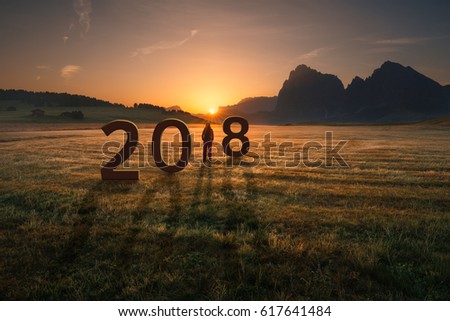 Young woman standing and watching the rising sun, uncertainty for 2018 new year. Future and time passing concept. Royalty-Free Stock Photo #617641484
