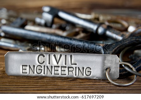 Photo of key bunch on wooden board and tag with letters imprinted on clean metal surface; concept of CIVIL ENGINEERING