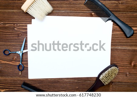 Hairdresser tools on wooden background. Blank card with barber tools flat lay. Top view on wooden table with scissors, comb and brush with empty white paper, free space. Barbershop, manhood concept
