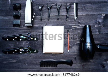 Hairdresser tools on wooden background. Blank card with barber tools flat lay. Top view on wooden table with scissors, comb, clipper and hairdryer with empty notebook and pencil, free space. 