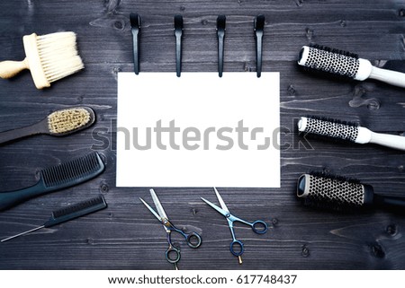 Hairdresser tools on wooden background. Blank card with barber tools flat lay. Top view on wooden table with scissors, comb, hairbrushes and hairclips with empty white paper, free space. Barbershop