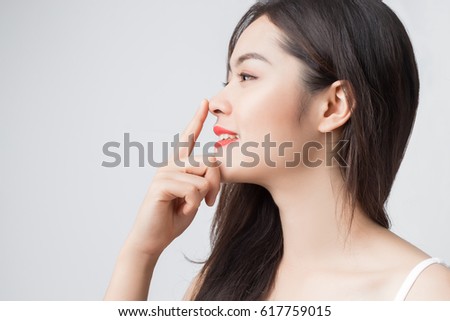 Young beautiful Asian woman with smiley face and red lips touching her nose. Royalty-Free Stock Photo #617759015