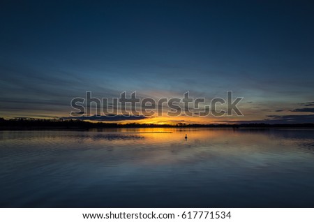 Katrineholm Sweden Europe. Beautiful nature and landscape photo of colorful sunset at lake. Nice calm, peaceful and joyful evening. Lovely outdoors picture. Birds and swan swimming in water.