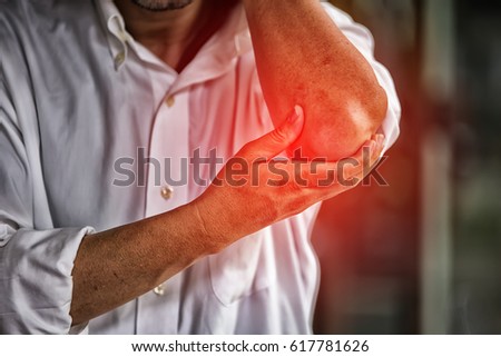 Businessman suffering from elbow pain at office High Dynamic Range tone Royalty-Free Stock Photo #617781626