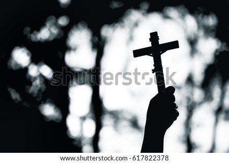 Human hand holding and lift of christian cross with light bokeh background