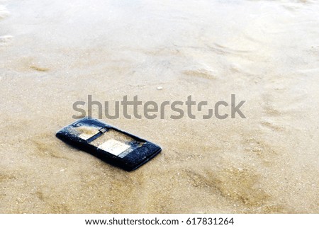 Close up of broken mobile phone drop on sea beach with copy space, High Contrast, Shallow Depth of Field