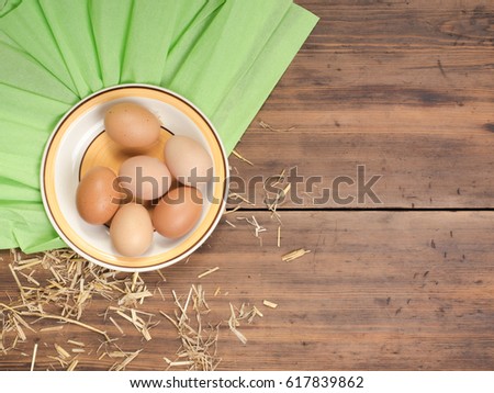 Rural eco background with brown chicken eggs, a piece of burlap and straw on the background of old wooden planks. The view from the top. Creative background for Easter cards or menu