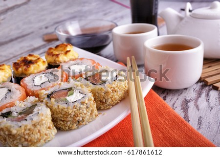 Sushi rolls served on white plate with black tea.
