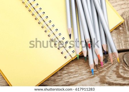 Drawing colourful pencils with notebook on brown wooden table