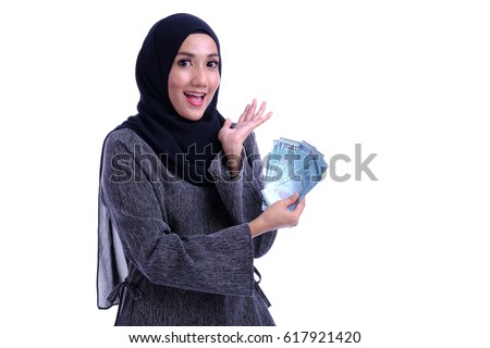 A pretty Muslim woman hold a money. Finance conceptual.  Royalty-Free Stock Photo #617921420