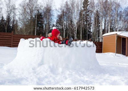 girl climbs the walls of a snow fortress
