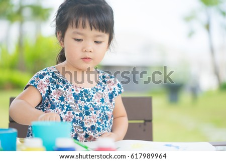Little asian girl painting at park outdoor in school.