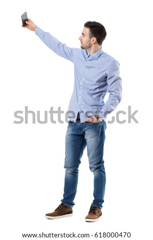 Side view of young businessman taking selfie photo with mobile phone. Full body length portrait isolated over white background.
