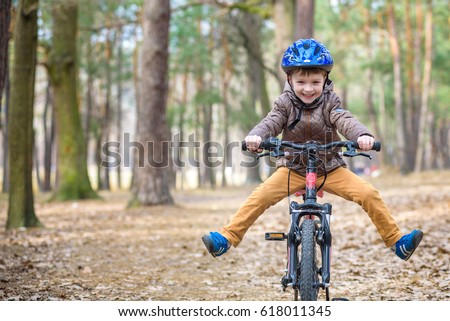 Happy kid boy of 3 or 5 years having fun in autumn forest with a bicycle on beautiful fall day. Active child wearing bike helmet. Safety, sports, leisure with kids concept