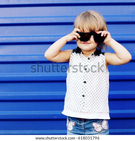 Portrait of cute happy baby girl in stylish clothes and sunglasses. Child summer outdoors