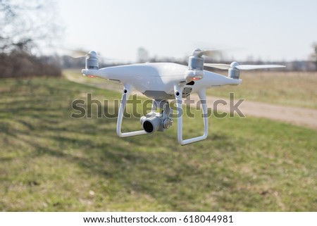 Copter soars from the ground to the sky against a background of green grass on the field. A drone with a high-resolution camera.