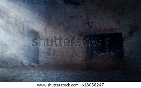 Light is shining in a cold room with a fireplace in old abandoned castle