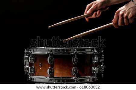 man plays musical percussion instrument with sticks closeup on a black background, a musical concept with the working drum