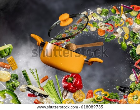 Fresh vegetable in water splash flying into a pot with wooden spoon, separated on dark background. Concept of food preparation and cooking