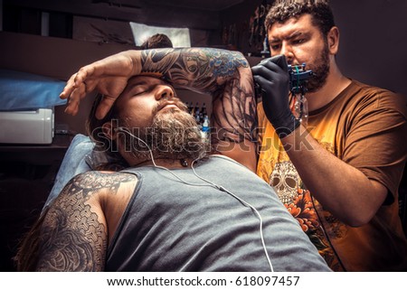 Tattoo specialist create tattoo in tattoo studio./Professional tattooist makes tattoo pictures in studio.