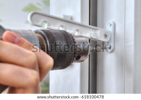 Drilling holes for fasteners to install the window limiter, close-up. Royalty-Free Stock Photo #618100478